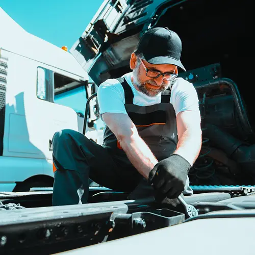 Mechanic performing roadside truck repair, representing professional fleet maintenance and emergency services